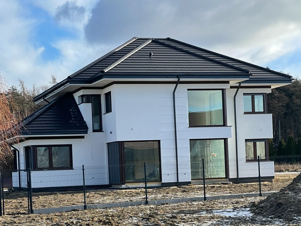 Elewacja domu nowoczesna biała fasada z dużymi oknami i czarnym pokryciem dachowym