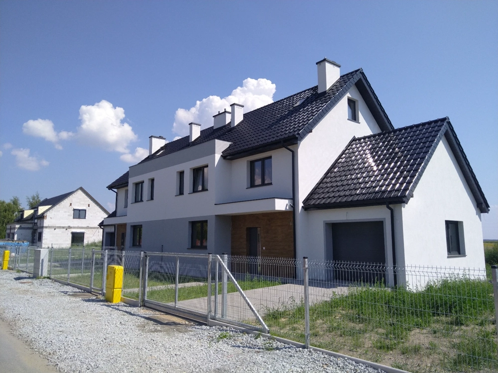 Elewacja domu nowoczesnego budynku z dachem dwuspadowym, bramą garażową i ogrodzeniem