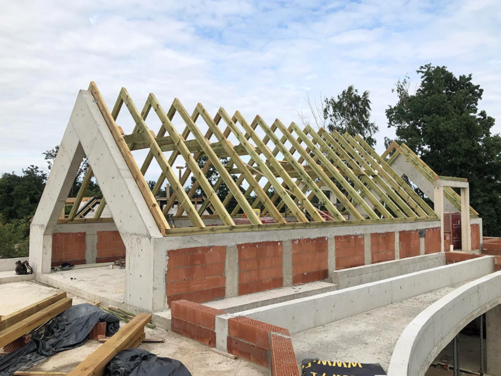 Konstrukcja więźby dachowej w stanie surowym otwartym z drewnianymi krokwiami i murami z cegły i betonu