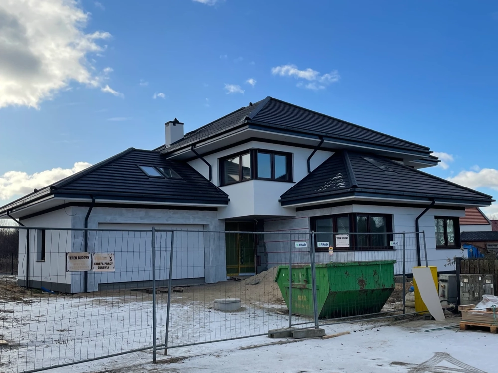 Nowoczesny dom w stanie surowym zamkniętym z czarnym dachem i białą elewacją