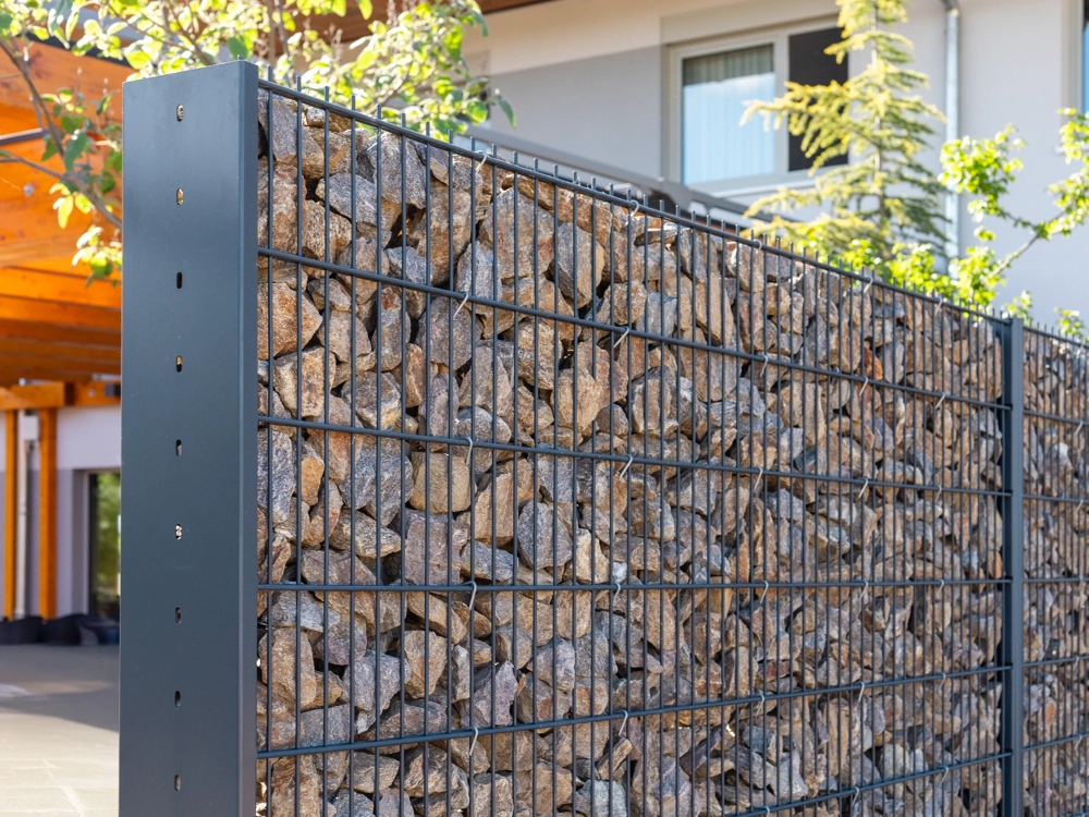 Ogrodzenia gabionowe wypełnione luzem kamieniami przed budynkiem