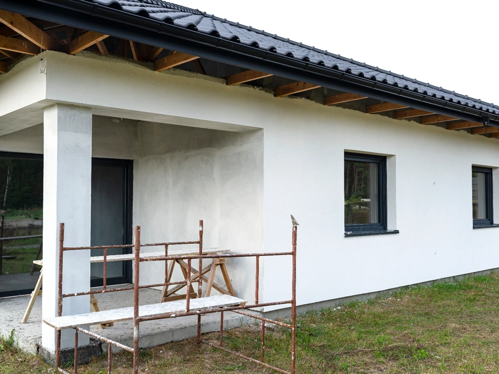 Rusztowanie przy białej elewacji domu podczas prac Tynki