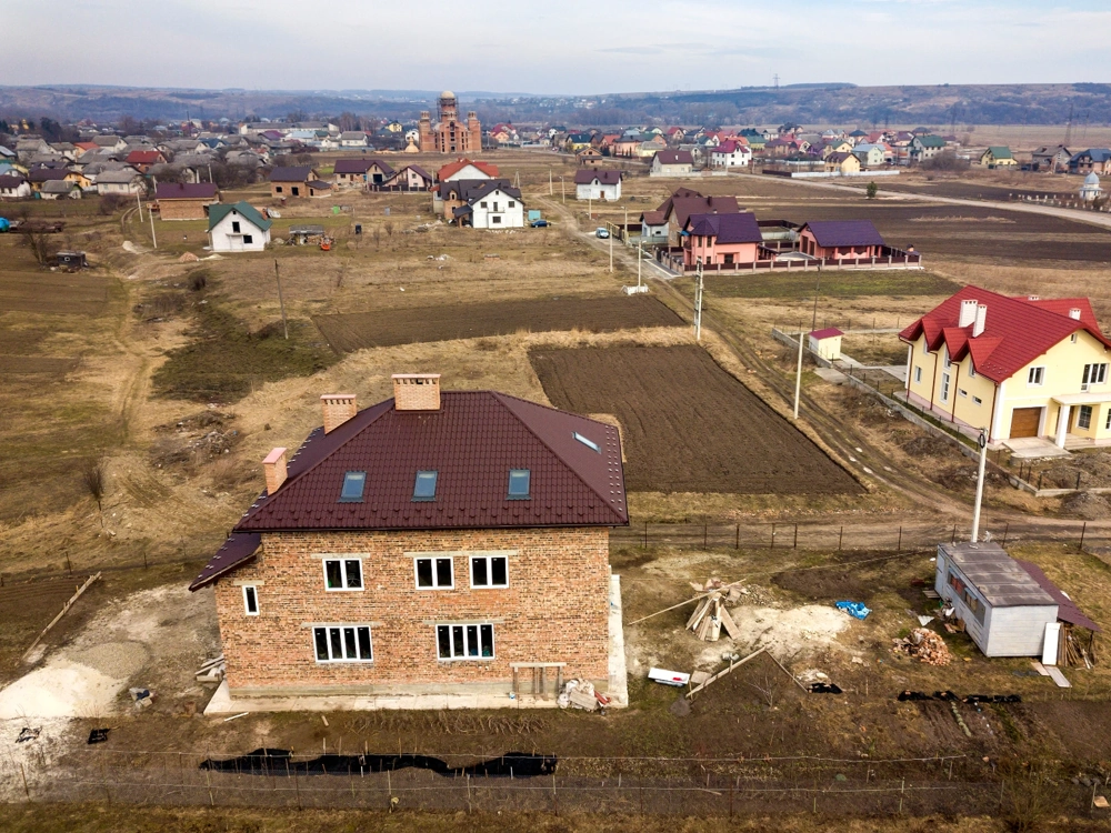 Widok z lotu ptaka na dom z dachem i oknami w stanie surowym zamkniętym na przygotowanym terenie budowy
