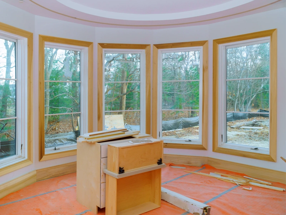 Montaż okien w pokoju surowym z drewnianymi ramami i zabezpieczoną folią podłogową