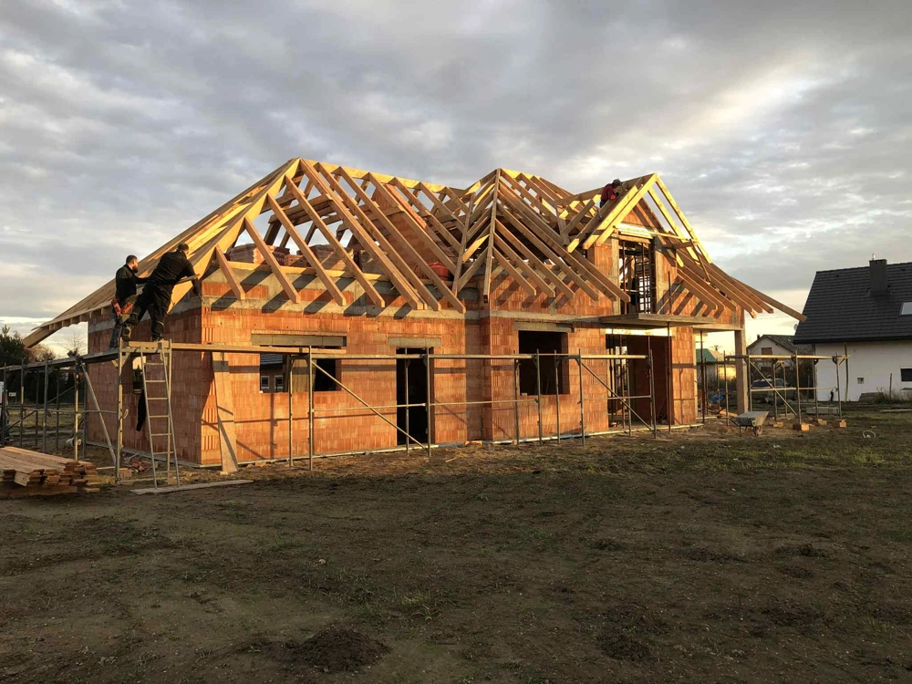 Montaż więźby dachowej na murowanym domu w stanie surowym otwartym ze stelażem i rusztowaniami