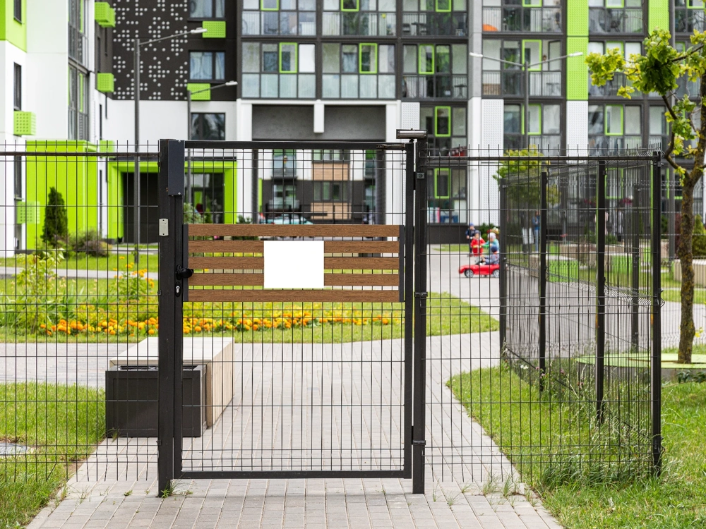 Metalowa furtka z drewnianymi panelami w ogrodzeniu nowoczesnego osiedla
