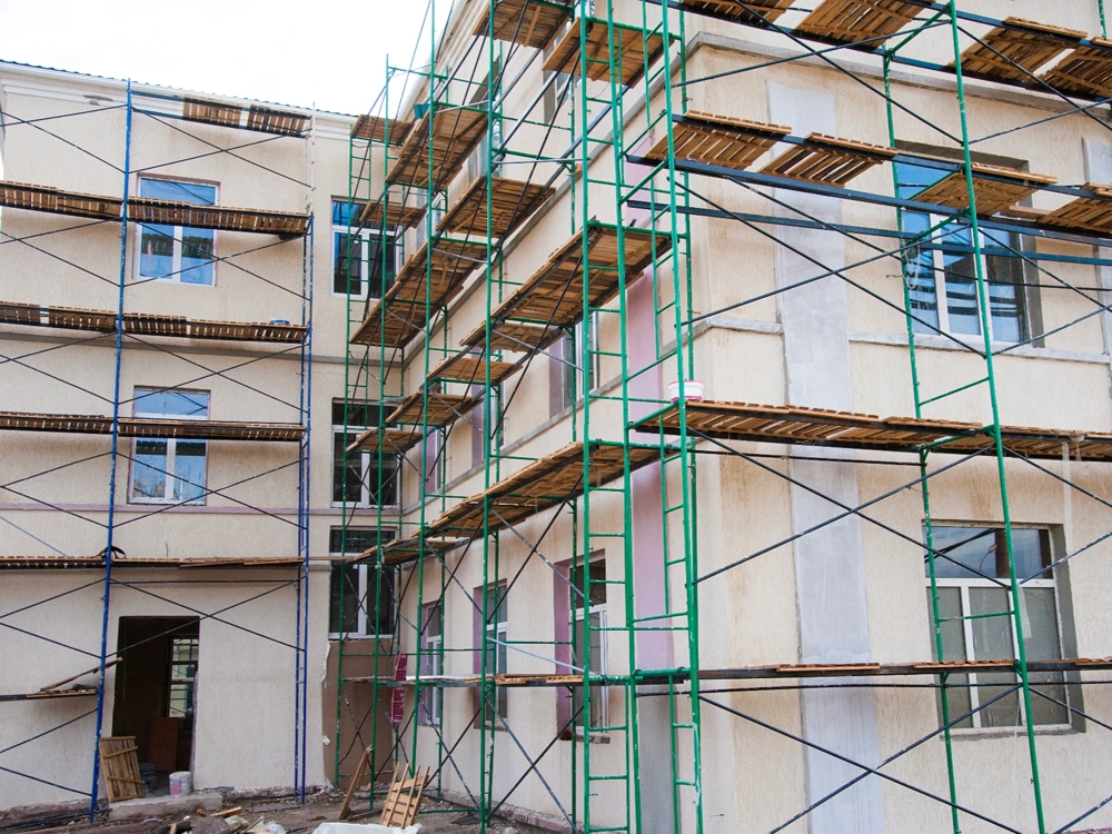 Rusztowania przy budynku mieszkalnym w trakcie elewacji domu z nakładaną warstwą tynku