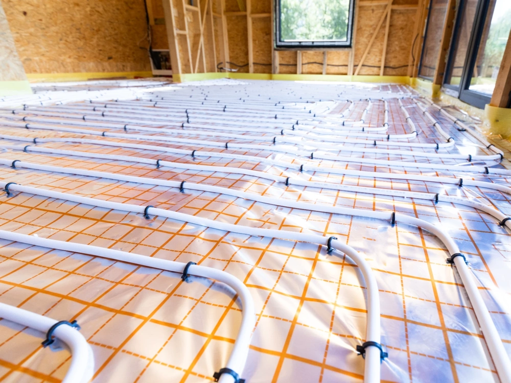 Instalacja ogrzewania podłogowego z białymi rurami na izolacji i siatce
