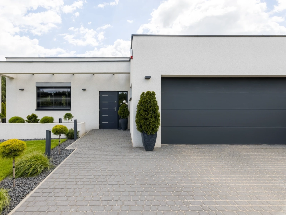 Nowoczesna elewacja domu z czarną bramą garażową