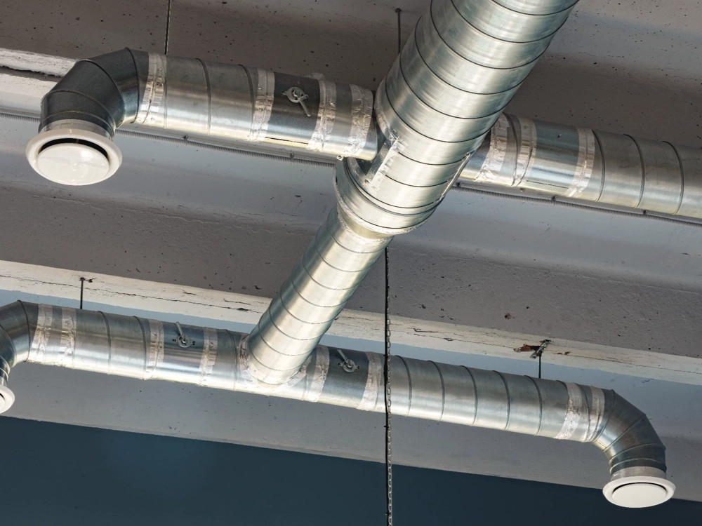 Widoczny układ stalowych przewodów wentylacyjnych rekuperacji pod sufitem