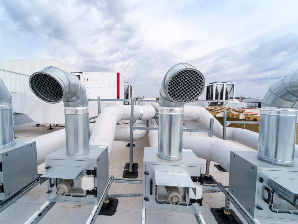 Kilka metalowych przewodów rekuperacji na dachu budynku