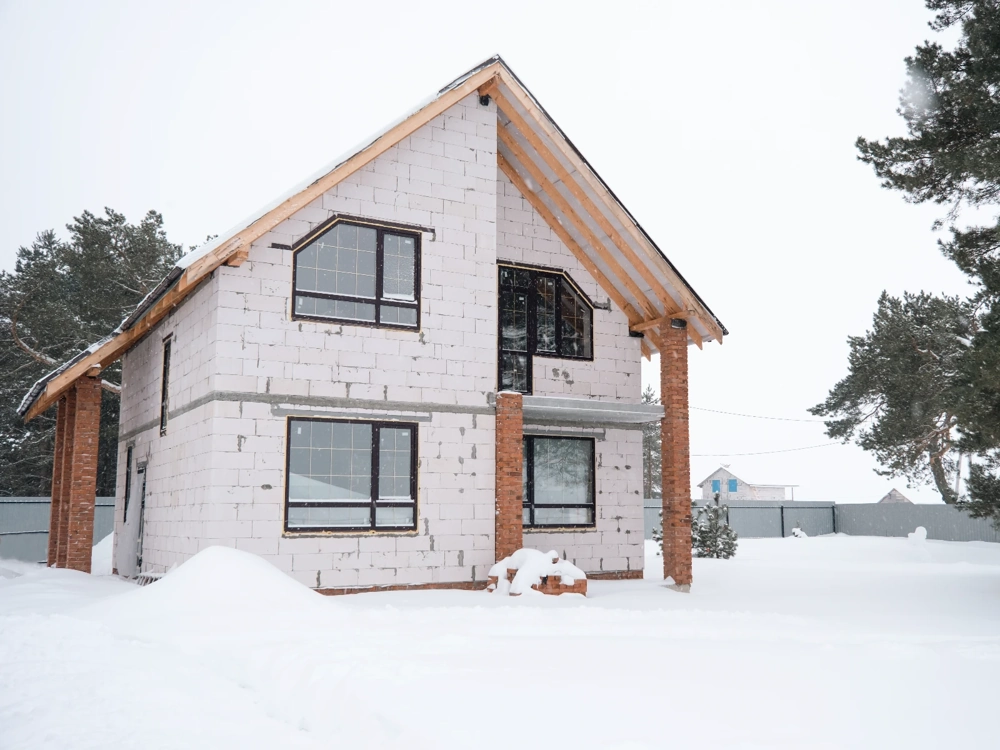 Dom w stanie surowym zamkniętym z murowanymi ścianami i zamontowanymi oknami w zimowej scenerii
