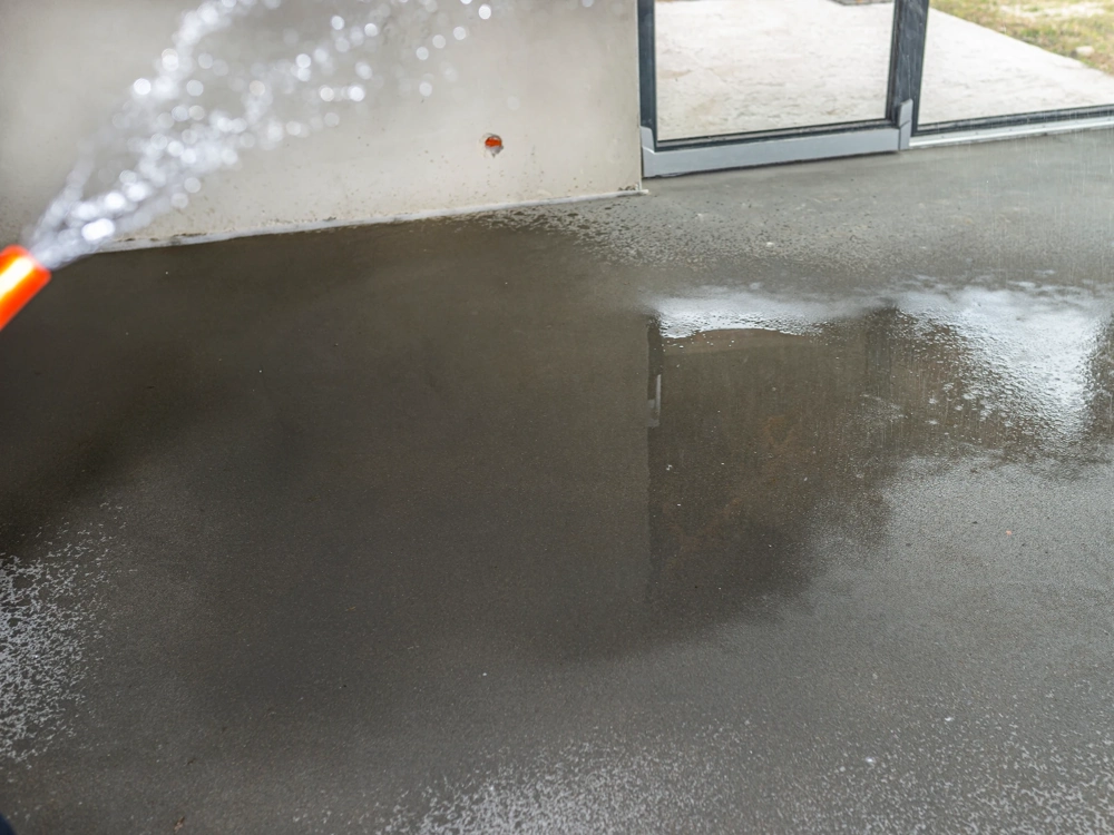 Zraszanie świeżej posadzki betonowej we wnętrzu budynku